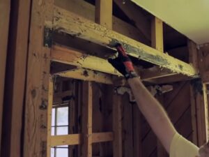 Image of termite damage in wood being pointed to by a pest control technician.